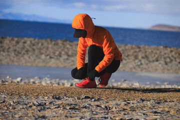 Woman runner tying shoelace at winter lakeside