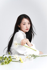 シャツを着た若い女性の花と撮影したシックなビューティーポートレート
