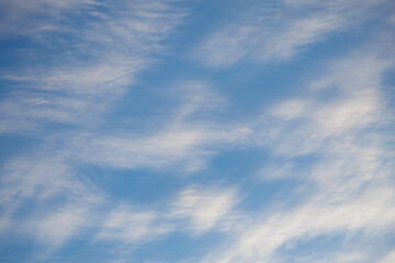 Soft white clouds dot a light blue sky, creating a tranquil scene suitable for a background or wallpaper usage.