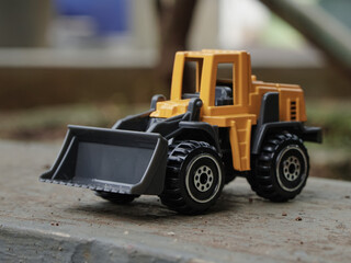 Yellow wheel loader or bulldozer toy outdoor with blurred background. construction image concept. side view photograph © thebaikers