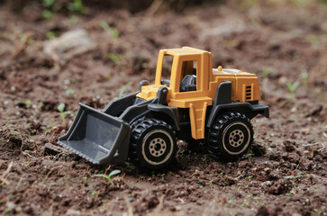 Yellow wheel loader or tractor toy on soil or ground background. construction image concept with heavy equipment.