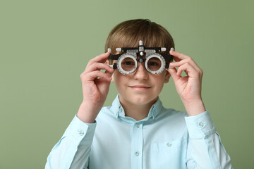 Little boy in optical trial frame on green background