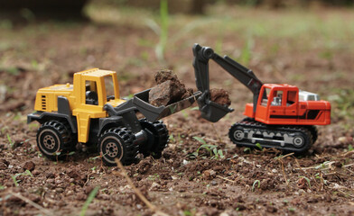 toy photography, Excavator toy and wheel loader toy working together loading soil at outdoor ground. excavation working on construction site concept.