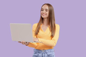 Young woman using laptop on lilac background