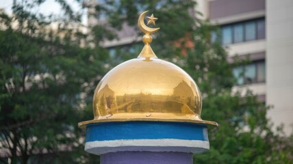 Golden dome mosque with crescent moon and star in greenery.