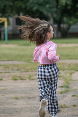A young beautiful girl frolics in a summer park.