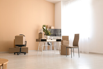 Workplace with cardboard boxes and chairs in office on moving day