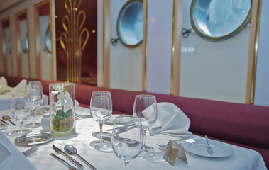 Formal and elegant ocean view dining room restaurant onboard historic luxury cruiseship or cruise ship liner with set tables in classic  interior design style and ceiling ambient lighting
