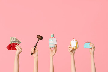 Female hands with auction gavel, wallets and antique vases on pink background