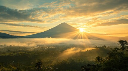 Early morning sky with golden rays of sunlight breaking through misty clouds over a mountain range