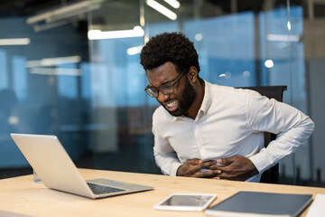 African American man businessman experiencing stomach pain. Discomfort appears severe indicating possible health issues. Facial expression suggests urgency in addressing digestive discomfort.