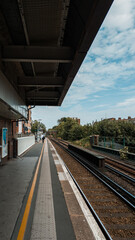 Naklejka premium Empty Train Station Platform with Railway Tracks Stretching into the Distance on a Cloudy Day 