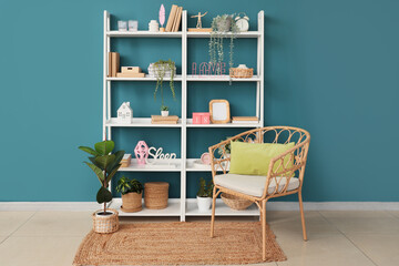 Armchair and shelving unit with books near blue wall in room