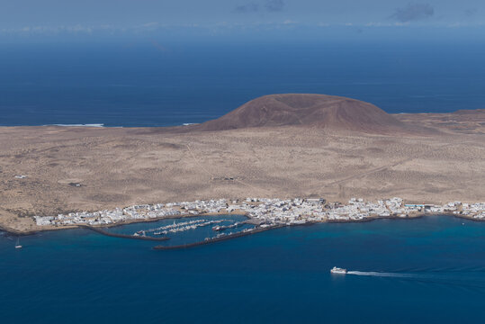 View of La Graciosa Island in the Canary Islands and the main town of Caleto Del Sebo with the ferry heading towards the port.