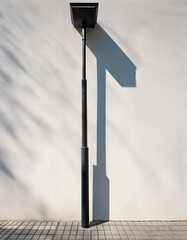 Minimalist Black Lamppost and Clean White Wall with Geometric Shadow