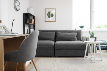 Interior of living room with modern grey sofa, coffee table and workspace