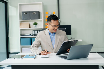 Naklejka premium Asian businessman typing laptop and tablet Placed at the table at the office.
