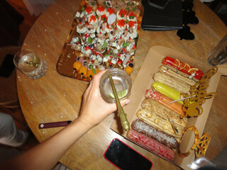 woman hand holding a drink at the bachelorettes party (hen party) at the table with decorated snacks and eclairs