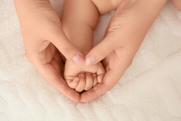 Mother holding her little baby's hand on bed, top view