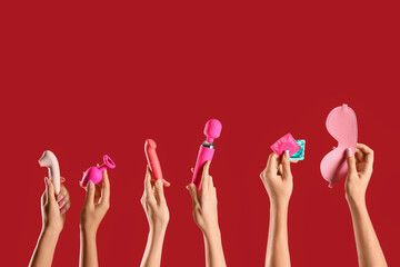 Women with sex toys and condoms on red background