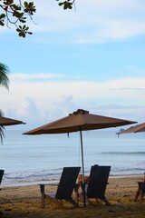 Plaża z leżakami, parasolkami i palmami, idealne miejsce do relaksu nad morzem. Spokojna atmosfera tropikalnego raju, z pięknym piaskiem i błękitnym niebem.