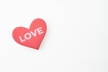 A red heart-shaped object with the word LOVE written on it placed on a white background