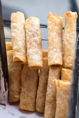 Risol bihun, a popular Indonesian fried snack, arranged in a metal rack with a blurred scene  in the background