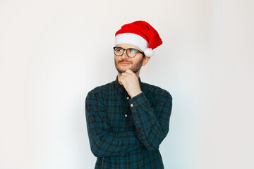 Portrait of young thoughtful man in Santa hat on white background.