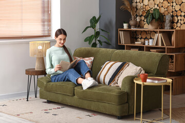 Young woman sitting on sofa with book in living room