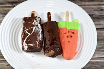 Assorted ice cream sticks of watermelon ice cream bar made of fruit shape and flavor, a half chocolate and half vanilla ice cream stick and chocolate ice cream coated with chocolate layer