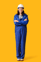 Young female construction worker with screwdriver on yellow background. Woman in male profession concept