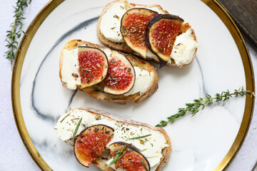 Plate of delicious fig bruschetta with ricotta cheese on white background, closeup