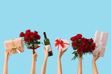 Female hands with roses, gift boxes and bottle of wine on blue background. Valentine's Day...