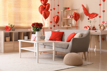 Engagement ring and and red roses on table in interior of living room decorated for Valentine's Day