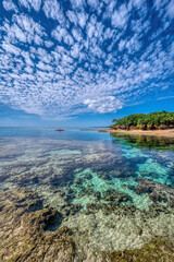 Crystal clear waters of Bise Beach, Motobu District, Okinawa main island. White sand beach with coral outcrops and small islands offshore.