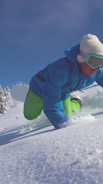 SLOW MOTION, CLOSE UP: Pro male snowboarder on scenic ride down breathtaking mountains falls into fresh snow. Cool freeride guy falls while riding his snowboard on sunny day in the perfect backcountry