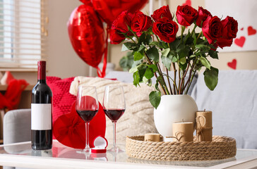 Red wine with engagement ring, gift for Valentine's Day and roses on table in living room