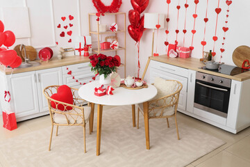 Stylish interior of light kitchen decorated for Valentine's Day with beautiful roses, gifts and tea set on table
