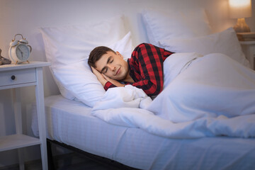 Young man sleeping in cozy bed at night