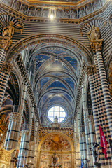 Interior of the Siena Cathedral, Duomo di Santa Maria Assunta - Siena, Italy. The interior of Siena Cathedral features magnificent columns, intricate arches, and vibrant banners.