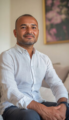 Confident hispanic businessman sitting on sofa smiling in modern office