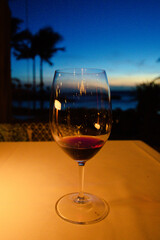 A glass of red wine served at sunset on a tropical island vacation