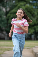 A young beautiful girl frolics in a summer park.