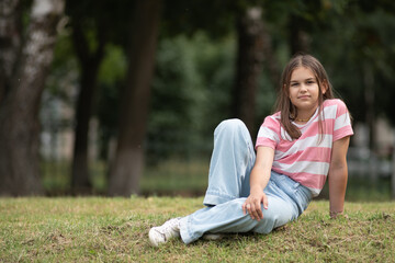 Fototapeta premium A young beautiful girl frolics in a summer park.