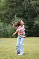 A young beautiful girl frolics in a summer park.