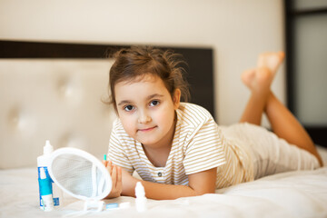 Cute little girl inserting contact lenses into her eye. Vision correction and ophthalmology for children.