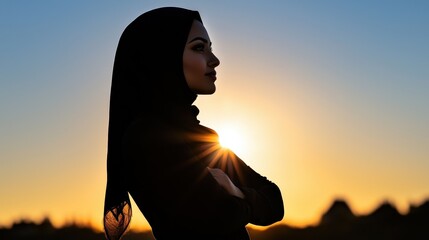 Silhouette of Woman in Hijab Against Vibrant Sunset Horizon