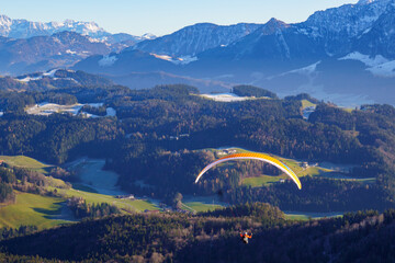 Paragliding. Flight over meadows and hills at the foot of the Zahmer Kaiser (Alps, Tyrol, Austria)