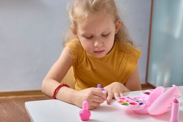 Cute Little Girl is Painting her Nails, Having Fun. Paint Child Nails. Varnish Kids Nails. Close-up.