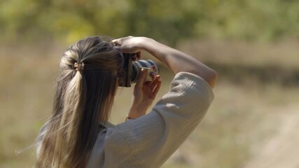 Woman photographing nature with camera in outdoor setting